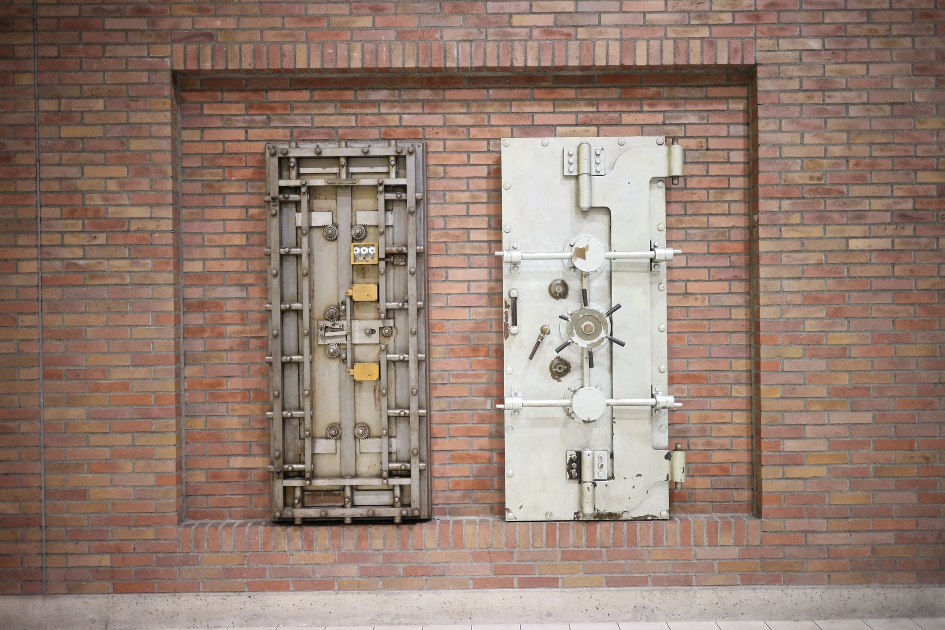 Dos puertas de caja fuerte de acero empotradas en un muro de ladrillo.
