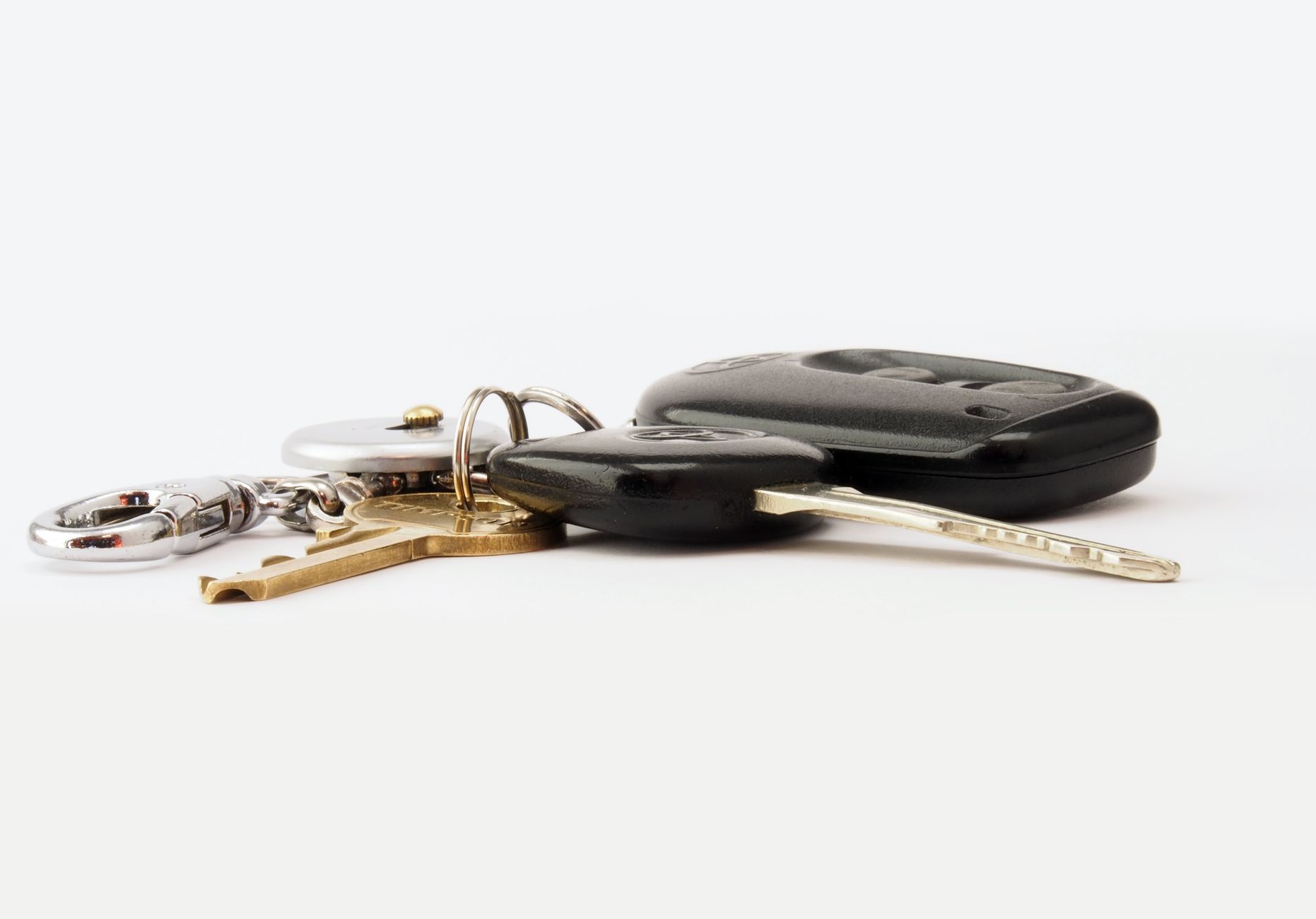 Llave de coche con mando a distancia y dos llaves más en un llavero, sobre fondo claro.
