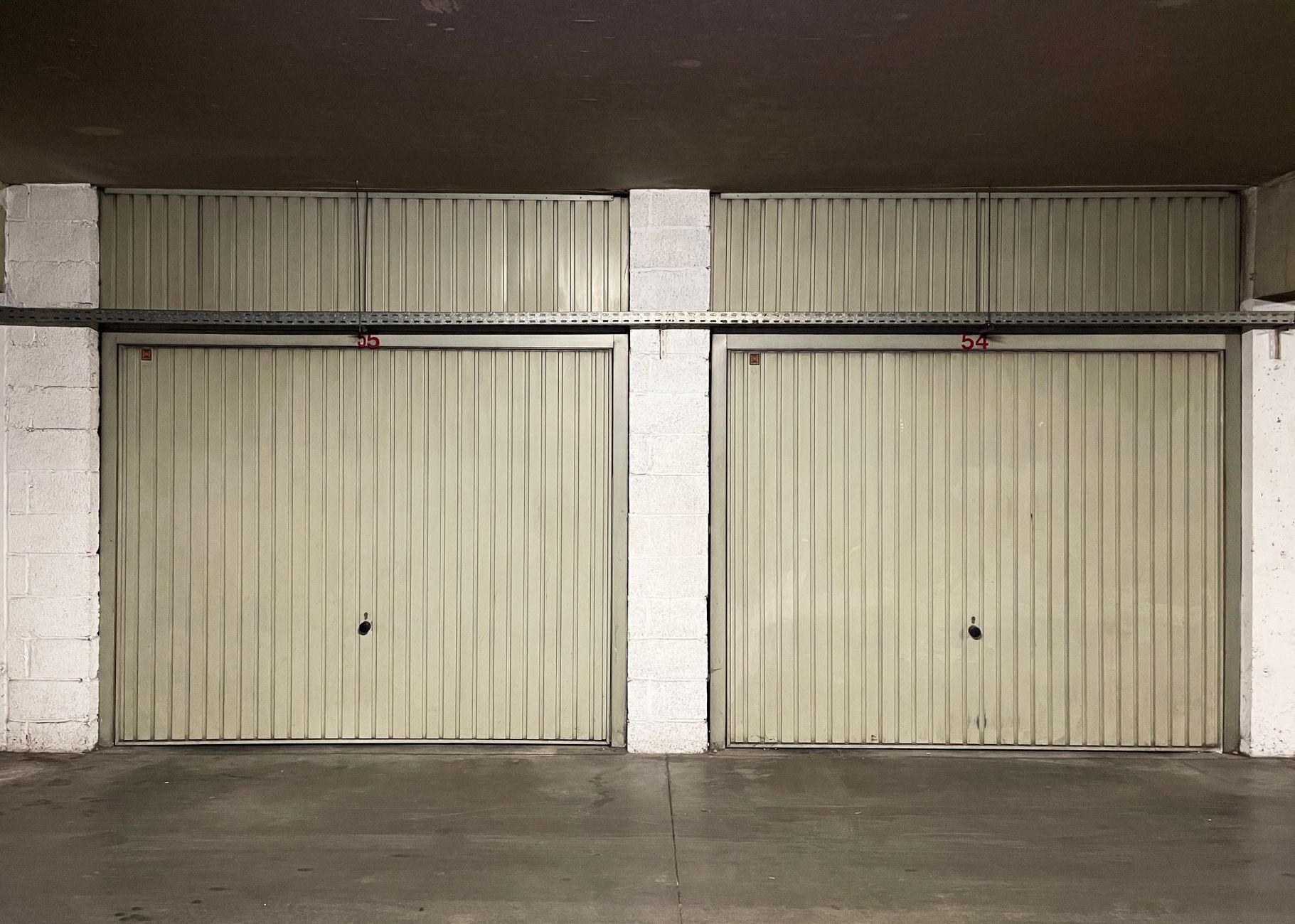 Dos puertas basculantes de garaje cerradas en un garaje comunitario.